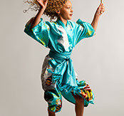 Young model leaping with loose blonde curls flying, wearing a teal and white kimono